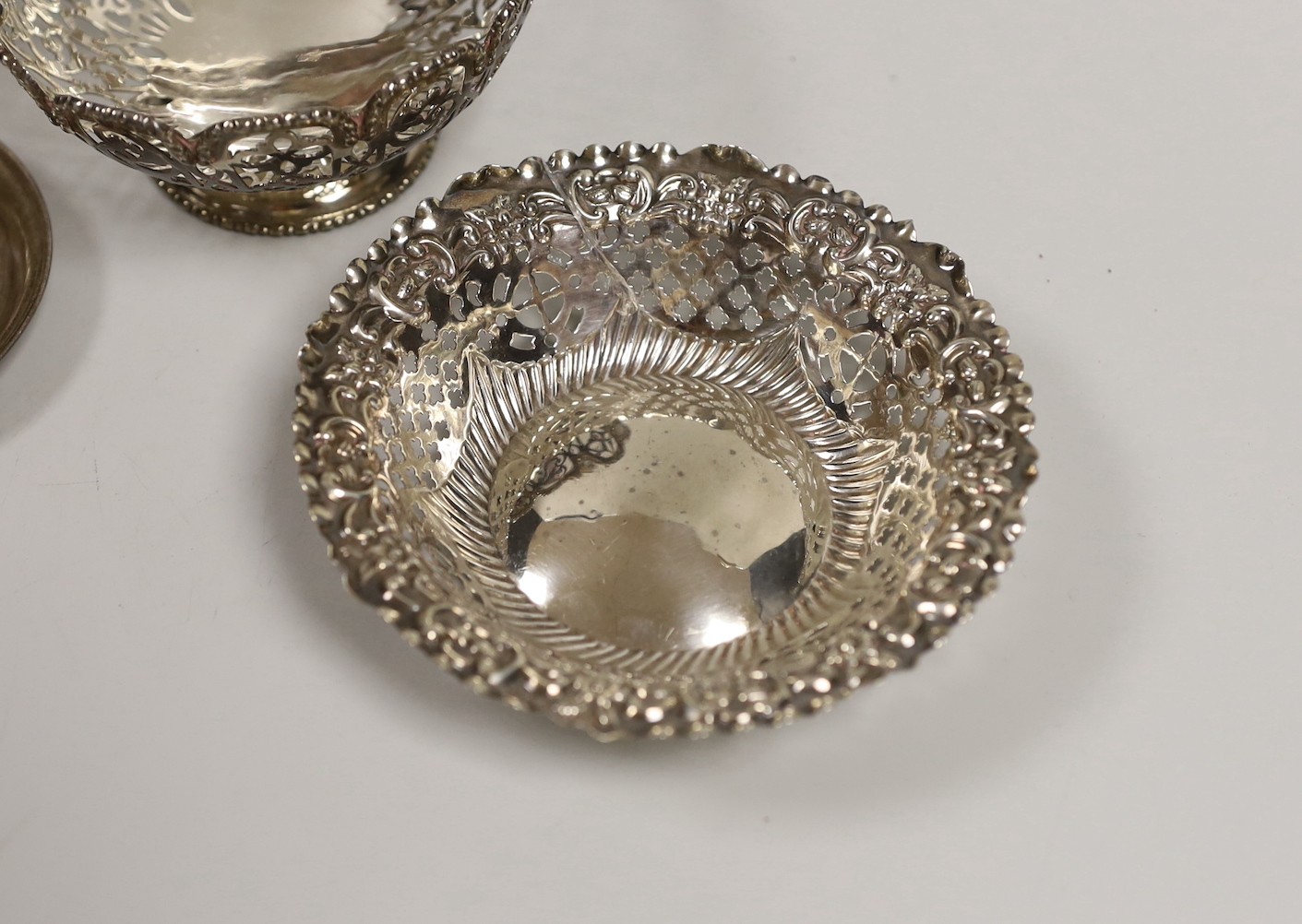 A pair of Edwardian pierced silver bonbon baskets, Nathan & Hayes, Birmingham, 1909, diameter 10.1cm, a pair of silver bonbon dishes, an Edwardian silver mounted glass hip flask, by Charles & George Asprey, London, 1908
